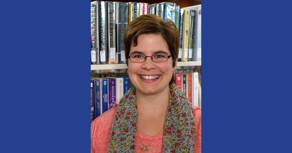 Terry Ehle, a children’s librarian from Two Rivers, Wisconsin, poses for a photo in front of a bookshelf of library books.