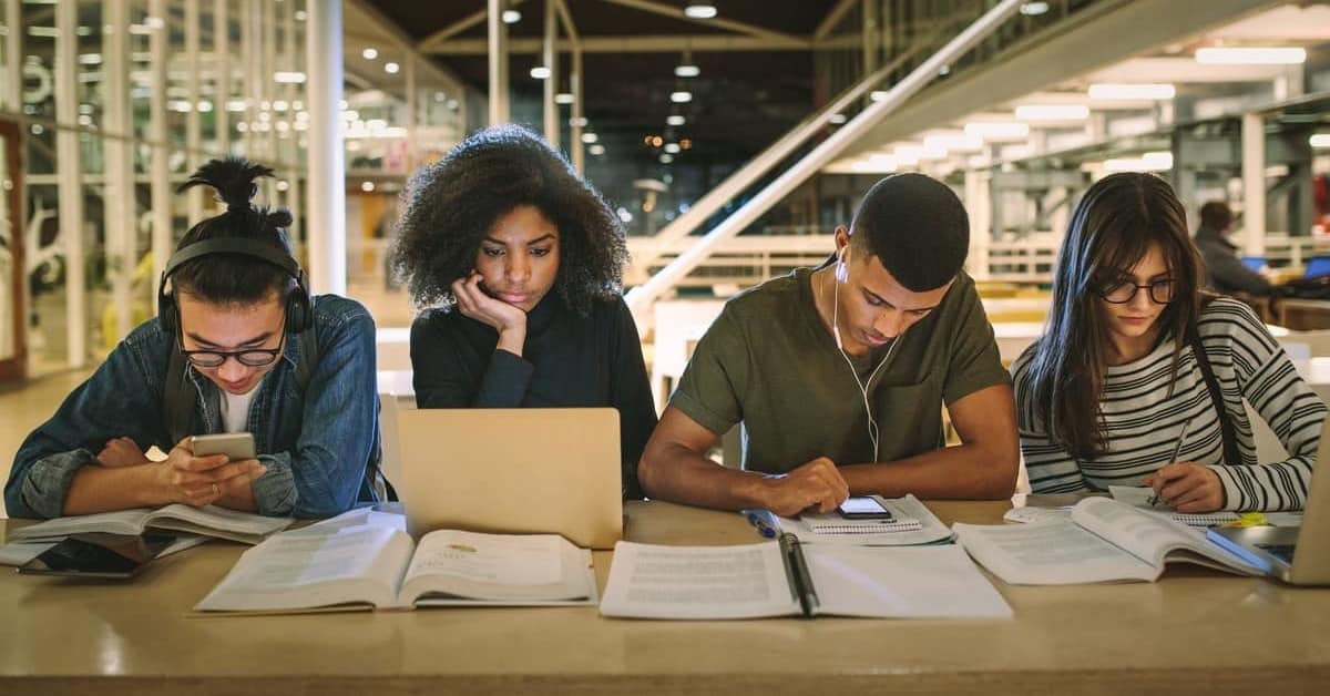 Generic image of students sitting at a table around a laptop computer"